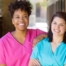 2 smiling women in scrubs represent RN supervisors and the good environment that can be promoted when they work together with caregivers for quality client care.