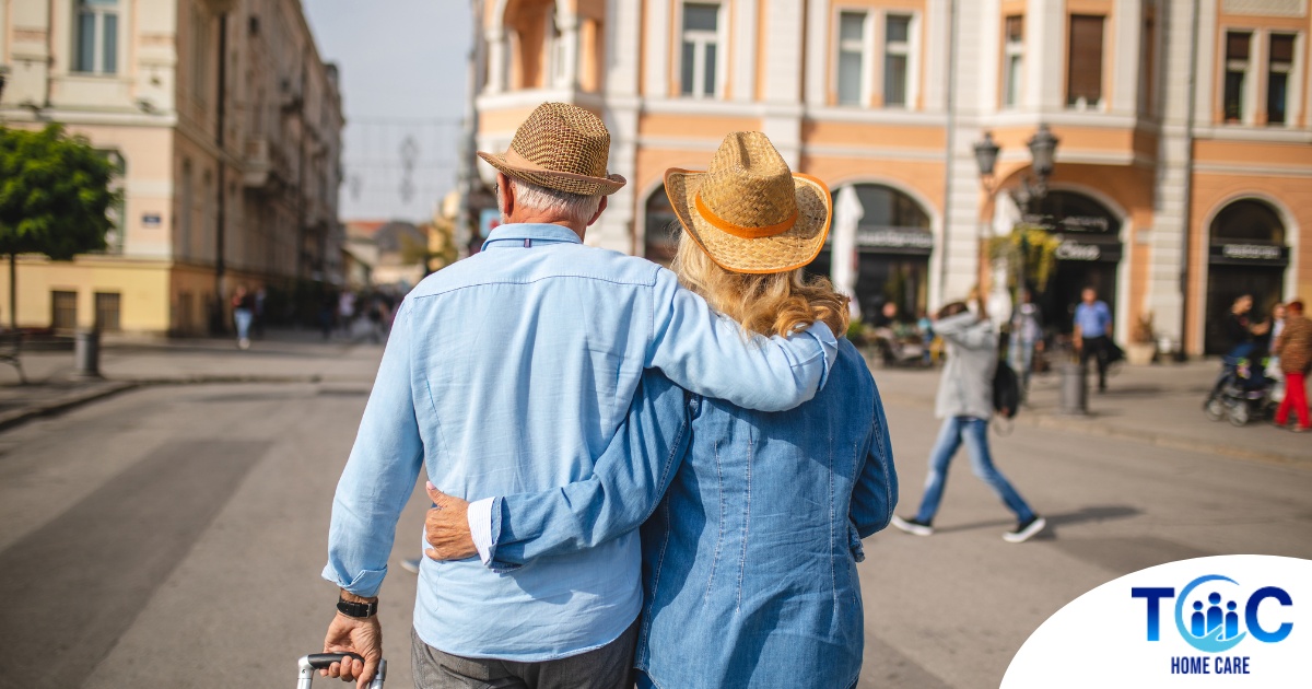 2 older adults hug while on vacation representing the successful outing that can still happen while caring for elderly loved ones.